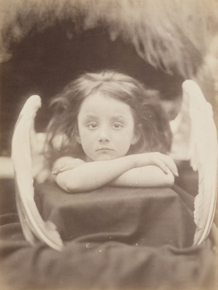 Περιμένω, 1872, Τζούλια Μάργκαρετ Κάμερον (by Julia Margaret Cameron). Η Κάμερον, μία από τις πρωτοπόρους γυναίκες φωτογράφους της εποχής της, άρχισε να ασχολείται με τη φωτογραφία στην ηλικία των 48 ετών.  Είχε το στούντιο της σ’ ένα διαμορφωμένο κοτέτσι στο πίσω μέρος του κήπου του σπιτιού της στο Isle of Wight, κι εκεί τράβηξε τα πορτρέτα διάσηπων προσωπικοτήτων της βικτωριανής εποχής, από τον Άλφρεντ Τένισον έως τον Κάρολο Δαρβίνο. Η συγκεκριμένη φωτογραφία της ανηψιάς της Rachel Gurney να φοράει φτερά κύκνου, παραπέμπει σε αναγεννησιακό ερωτιδέα.